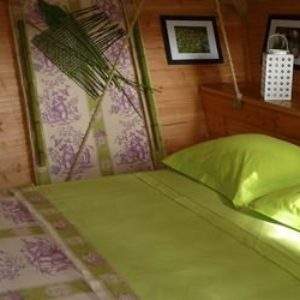 Hébergement insolite : cabane en bois avec lit double et décor floral apaisant.