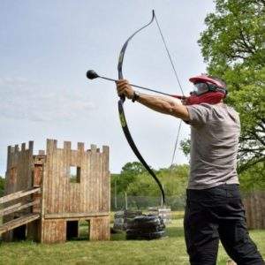 Hébergement insolite en Basse-Normandie, avec un homme tirant à larc près dun château en bois.