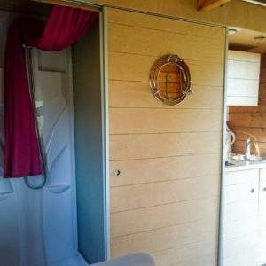 Hébergement insolite en bois avec douche et kitchenette, ambiance chaleureuse et moderne.