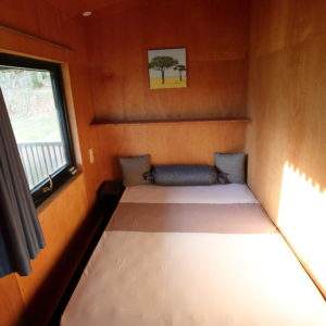 Cabane en bois à Basse-Normandie, intérieur chaleureux avec lit confortable et vue.