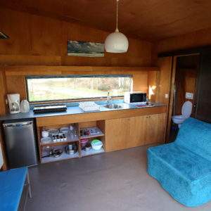 Hébergement insolite en Basse-Normandie : intérieur moderne avec cuisine et canapé bleu.