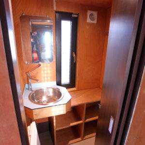 Hébergement insolite en Basse-Normandie : intérieur moderne avec lavabo et rangements.