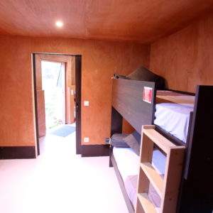 Chambre en cabane avec lits superposés et murs en bois chaleureux en Basse-Normandie.