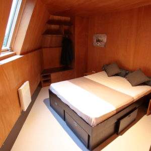 Chambre en bois dans un hébergement insolite en Basse-Normandie, ambiance chaleureuse.