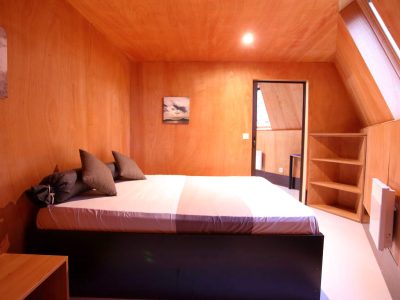 Chambre en bois dans un hébergement insolite en Basse-Normandie, ambiance chaleureuse.