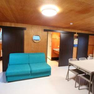 Hébergement insolite en Basse-Normandie, intérieur moderne avec canapé turquoise et table.