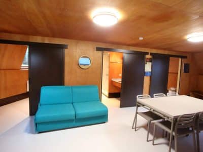 Hébergement insolite en Basse-Normandie, intérieur moderne avec canapé turquoise et table.