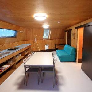 Hébergement insolite en Basse-Normandie, intérieur en bois avec cuisine et salon moderne.