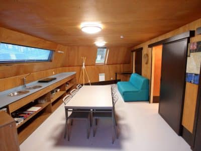 Hébergement insolite en Basse-Normandie, intérieur en bois avec cuisine et salon moderne.