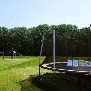 Hébergement insolite : un trampoline dans un grand espace vert, entouré darbres.