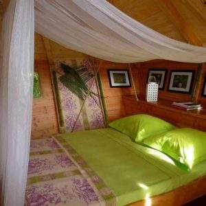 Hébergement insolite en cabane avec lit double et décor floral apaisant.