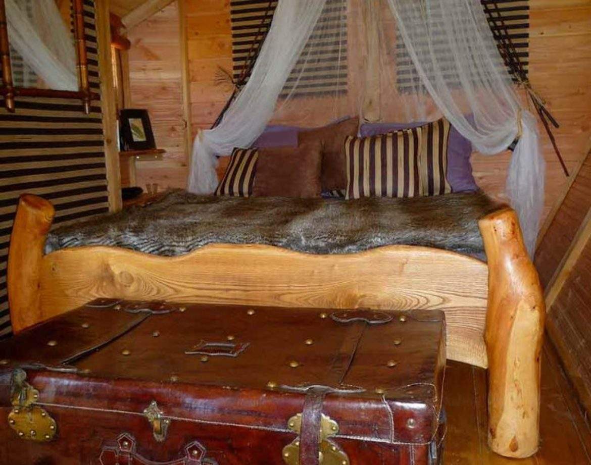 Chalet en bois avec lit douillet et coffre ancien, ambiance chaleureuse et rustique.