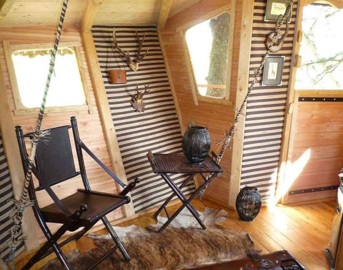 Hébergement insolite en cabane avec chaises suspendues et décor en bois chaleureux.