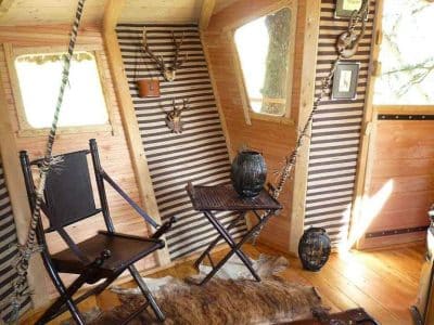 Hébergement insolite en cabane avec chaises suspendues et décor en bois chaleureux.