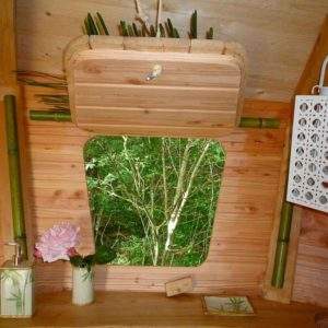 Intérieur dune cabane en bois, avec vue sur la nature et des éléments décoratifs en bambou.