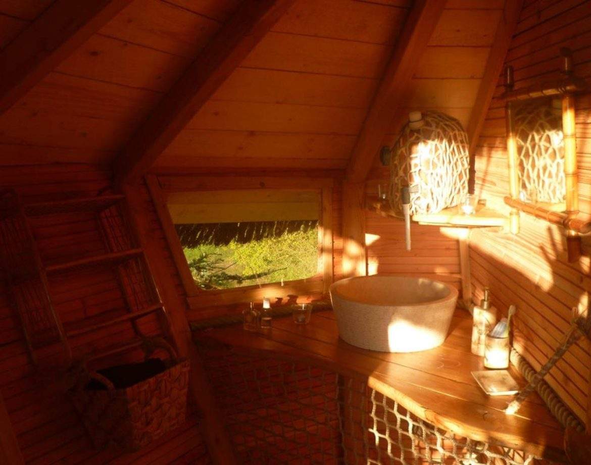 Cabane en bois chaleureuse avec un lavabo en osier et lumière naturelle.