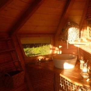 Cabane en bois chaleureuse avec un lavabo en osier et lumière naturelle.