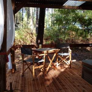 Cabane en bois en Aquitaine, avec terrasse en bois et chaises confortables.