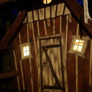 Cabane insolite en Aquitaine, avec fenêtres illuminées et porte en bois sculpté.