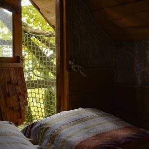 Cabane perchée en Midi-Pyrénées, avec vue sur la nature et literie colorée.