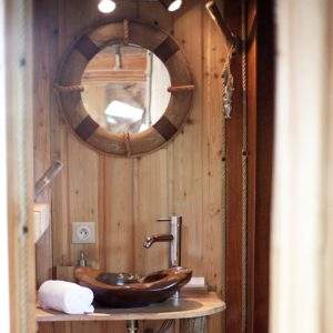 Salle de bain en bois dans un hébergement insolite, avec un lavabo en pierre.