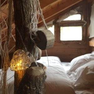 Cabane en bois avec éclairage doux et literie confortable, ambiance chaleureuse.