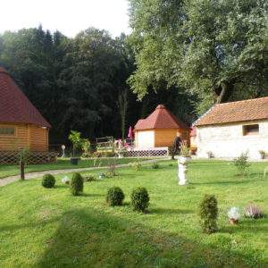 Hébergement insolite en chalets en bois, entouré dun jardin verdoyant et fleuri.