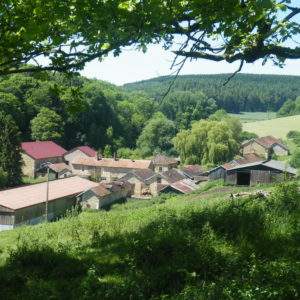 Hébergement insolite en pleine nature, avec des bâtiments en pierre et un toit rouge.