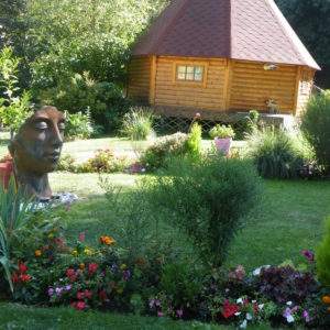 Hébergement insolite en rondins à Champagne-Ardennes, entouré de fleurs colorées.