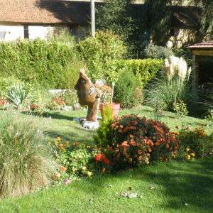 Hébergement insolite en Champagne-Ardenne, avec un jardin fleuri et une sculpture en bois.
