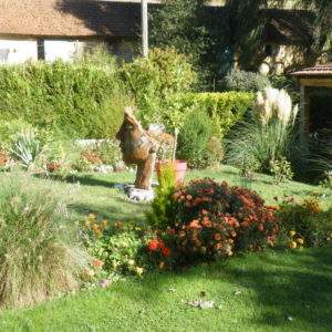 Hébergement insolite en Champagne-Ardennes, avec un jardin fleuri et une sculpture en bois.