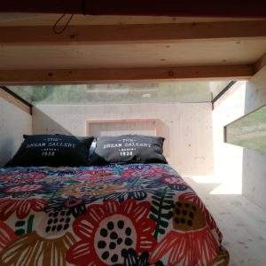 Cabane en bois avec lit douillet et vue panoramique sur la nature environnante.