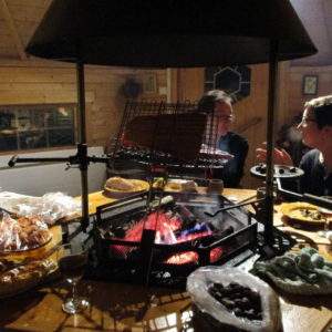 Cabane en bois à Champagne-Ardennes, avec un feu de cheminée et des convives autour dune table.