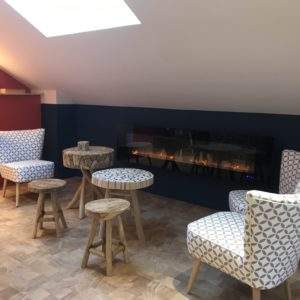 Hébergement insolite en Auvergne-Rhône-Alpes, salon cosy avec fauteuils modernes et cheminée.