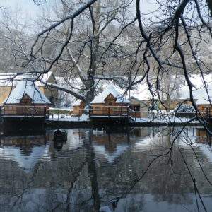 Hébergement insolite : cabanes en bois au bord dun étang, sous la neige.