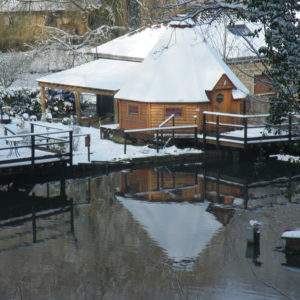 Hébergement insolite en bois à Champagne-Ardennes, entouré de neige et deau.