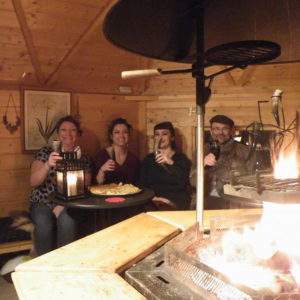 Hébergement insolite en cabane en bois, avec un feu chaleureux et des convives joyeux.