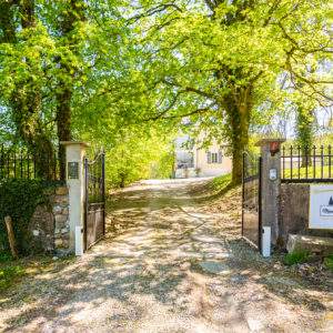Entrée dun hébergement insolite en Auvergne-Rhône-Alpes, entouré darbres verdoyants.