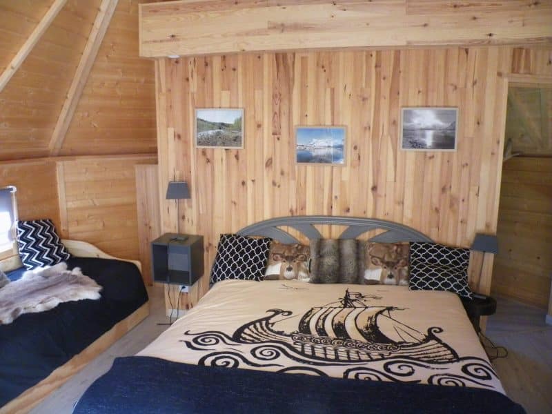 Chalet en bois avec lit décoré dun motif de bateau et murs en lambris.