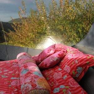 Tente transparente avec literie colorée, vue sur la nature en Auvergne-Rhône-Alpes.
