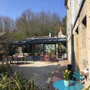 Hébergement insolite en Basse-Normandie, avec véranda vitrée et jardin fleuri.