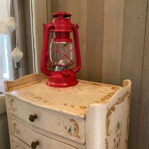 Hébergement insolite en Basse-Normandie, avec une lampe à pétrole rouge sur une commode vintage.