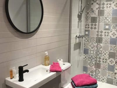 Salle de bain moderne dun hébergement insolite en Auvergne-Rhône-Alpes, avec carrelage coloré.