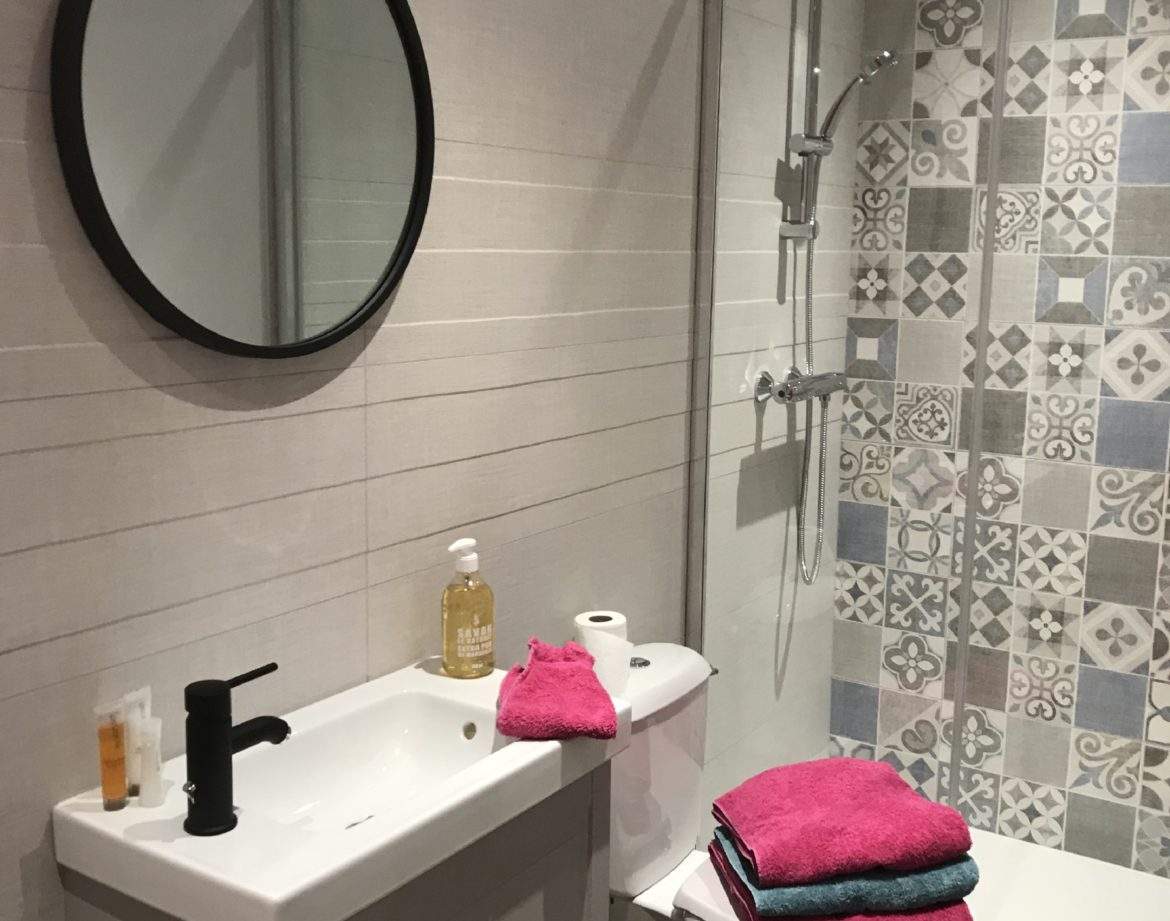 Salle de bain moderne dun hébergement insolite en Auvergne-Rhône-Alpes, avec carrelage coloré.