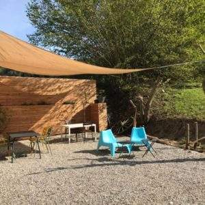 Hébergement insolite en Auvergne-Rhône-Alpes avec terrasse ombragée et mobilier coloré.