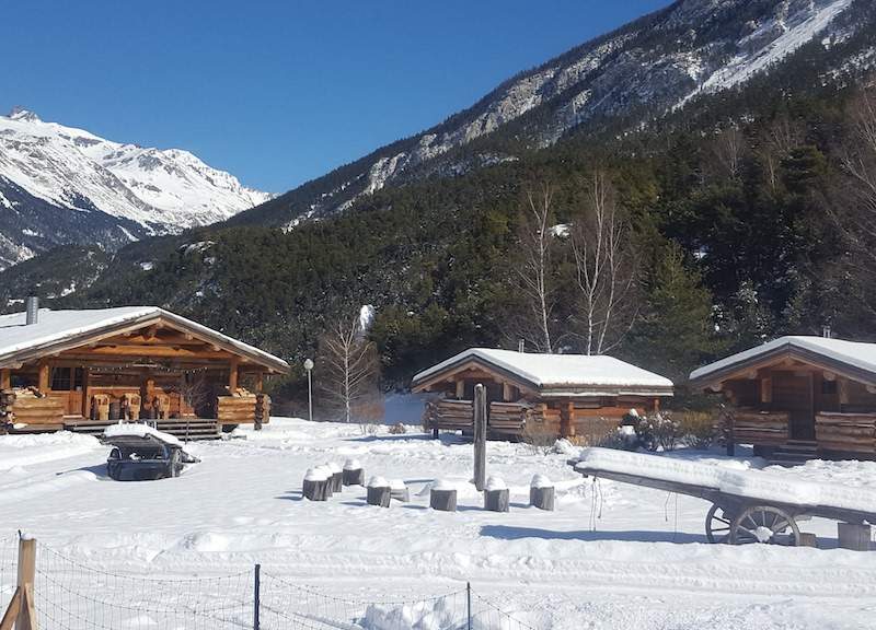 Chalets en bois au cœur des montagnes, entourés de neige éclatante.