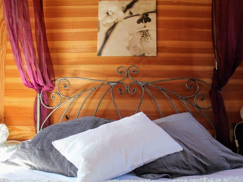 Chalet cosy avec lit en fer forgé et décoration en bois chaleureux.