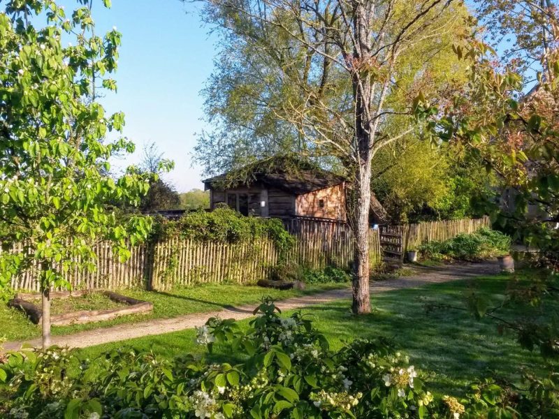 Charmante cabane en bois entourée de verdure et de jardins fleuris.