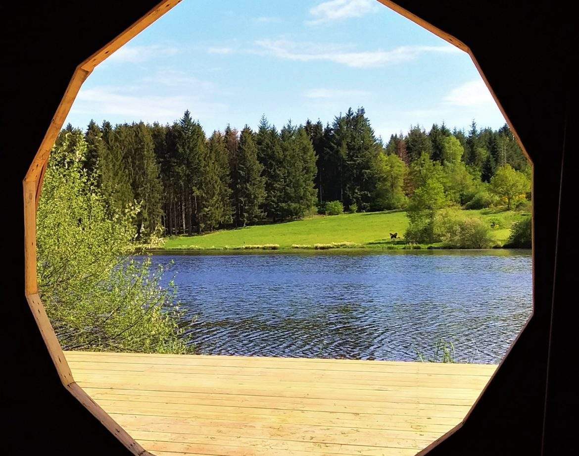 Hébergement insolite en Auvergne : cabane avec vue circulaire sur un lac et la forêt.