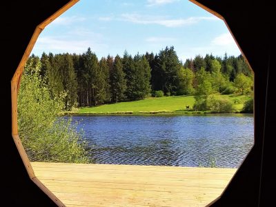 Hébergement insolite en Auvergne : cabane avec vue circulaire sur un lac et la forêt.